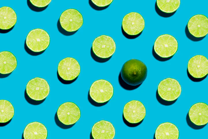 Sliced Open Geen Limes on Symmetrical Blue Background with one peeled open Sliced Open Geen Limes on Symmetrical Blue Background with one peeled open